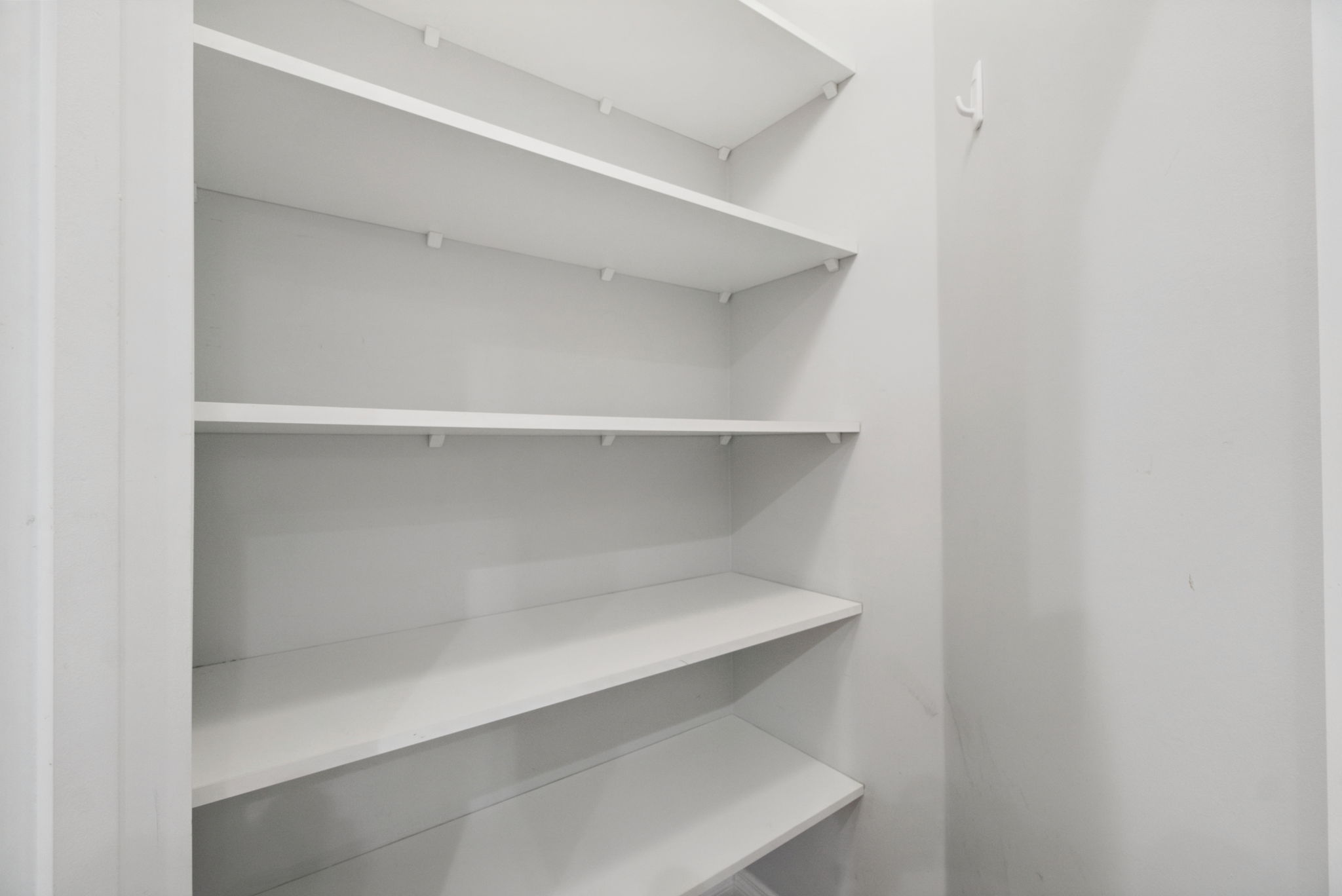 The walk-in pantry beside the kitchen, lined with white shelving.