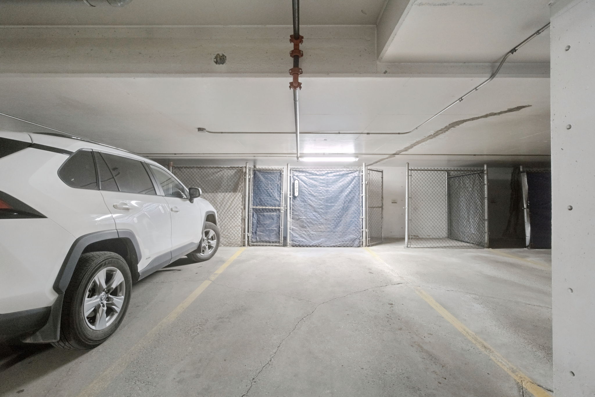 The heated underground parkade, with a parked SUV beside the secured storage cages.